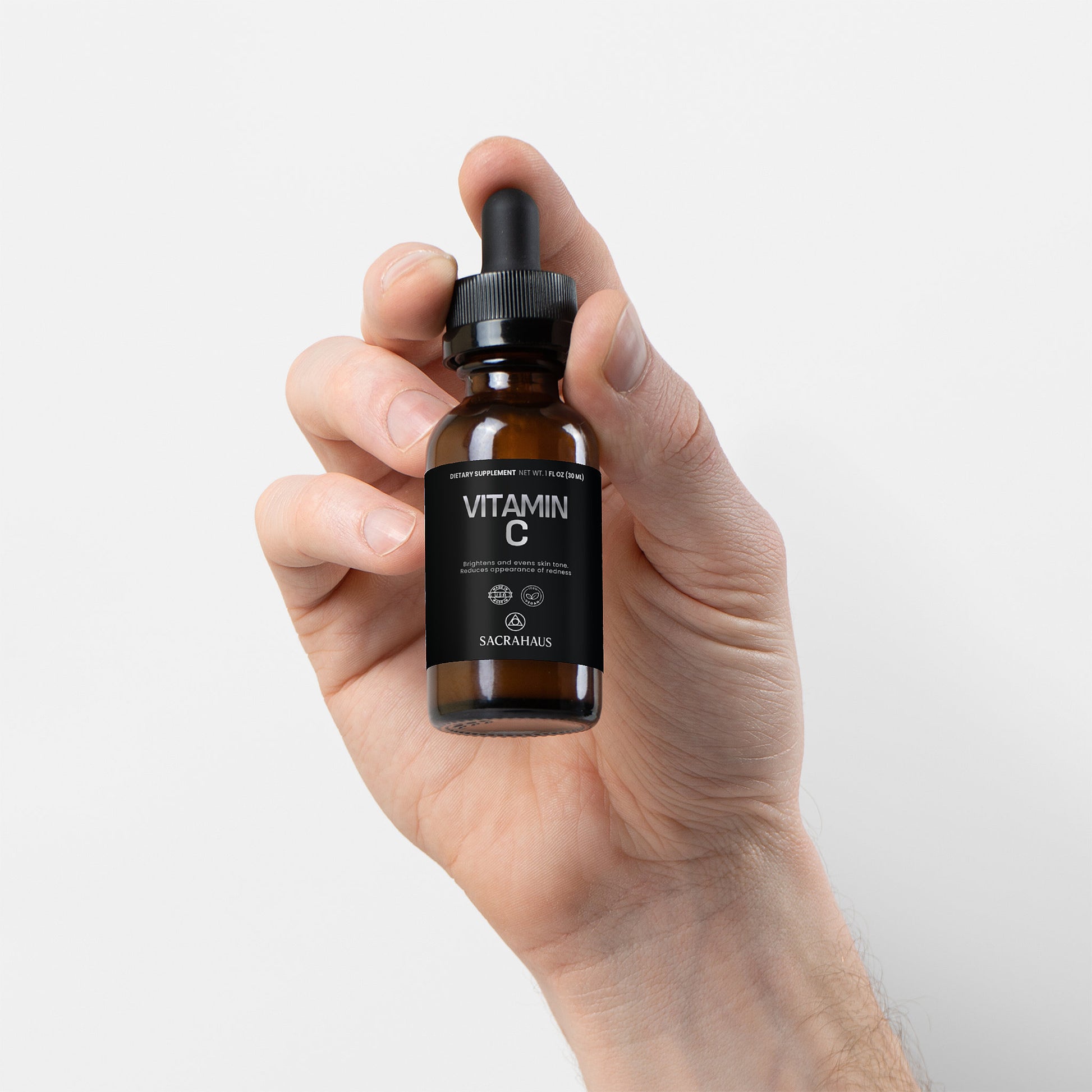 SACRAHAUS vegan vitamin C serum bottle held in a hand for radiant skin improvement