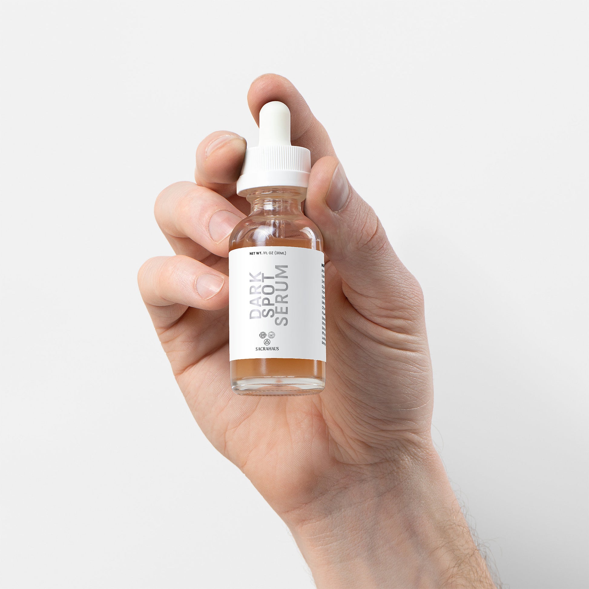 SACRAHAUS dark spot serum for sensitive skin in a glass dropper bottle held in a hand