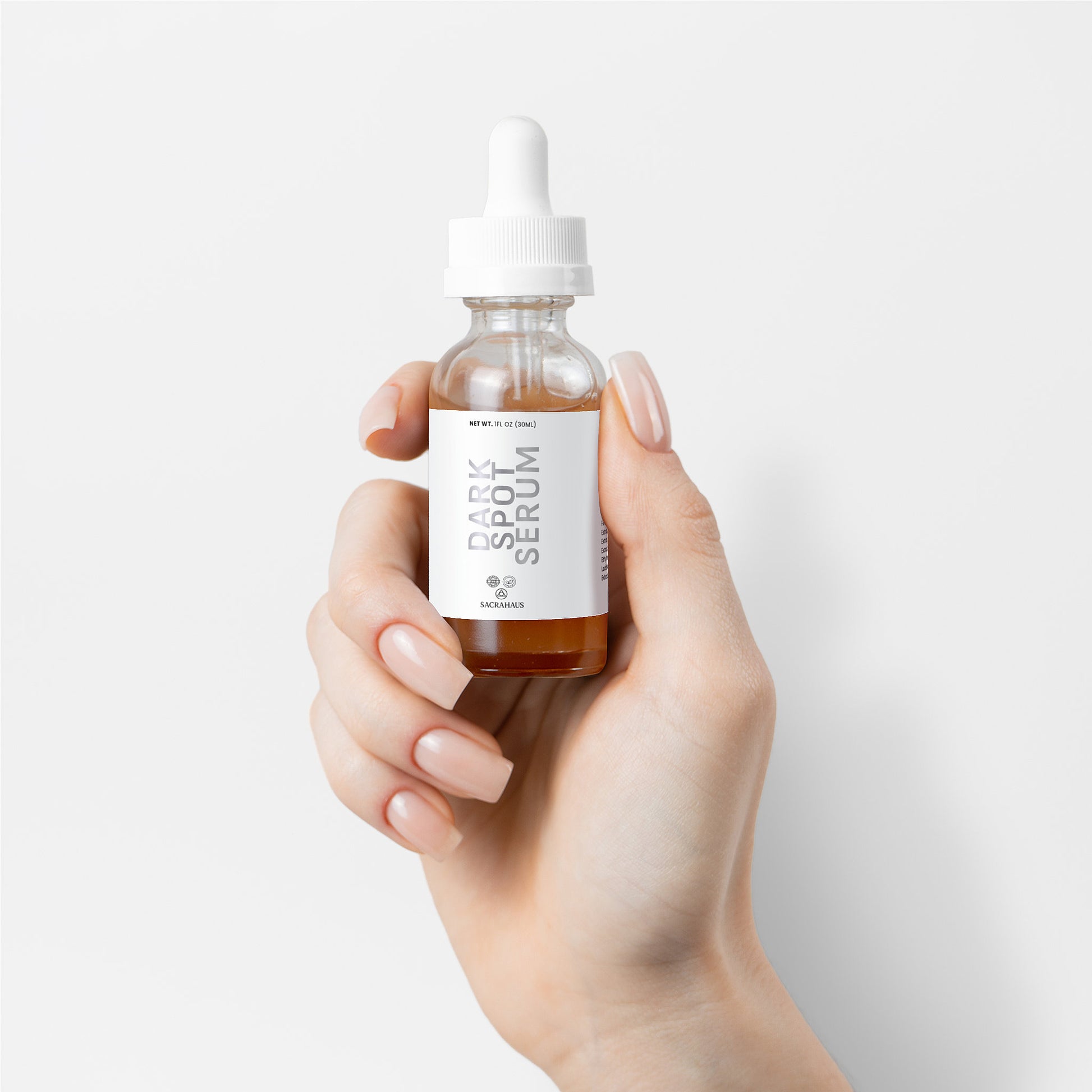 SACRAHAUS Dark Spot Serum for Sensitive Skin in a dropper bottle held by a woman's hand