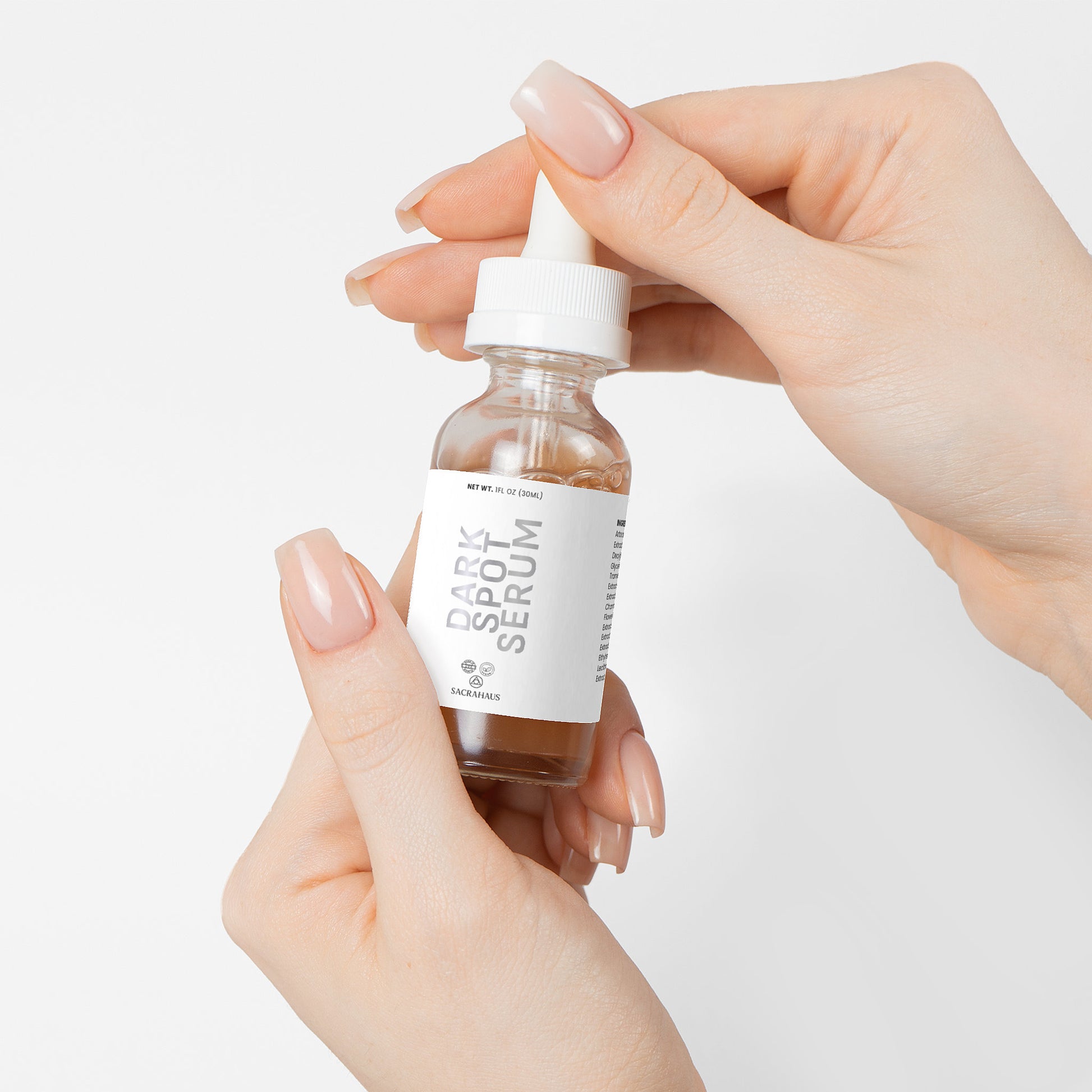 SACRAHAUS dark spot serum for sensitive skin in a glass dropper bottle held by hands